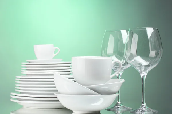 Assiettes, tasses et verres propres sur fond vert — Photo