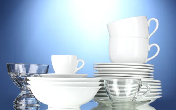 Tigelas vazias, pratos, copos e copos sobre fundo azul — Fotografia de Stock