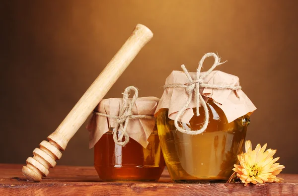 Két üveget, a méz és a fából készült drizzler a tábla, sárga háttér — Stock Fotó