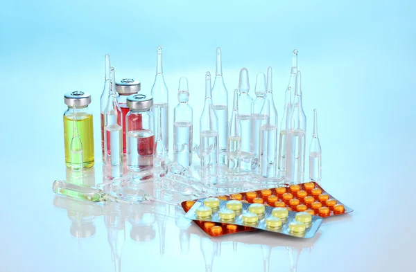 Tabletten en ampullen op blauwe achtergrond — Stockfoto