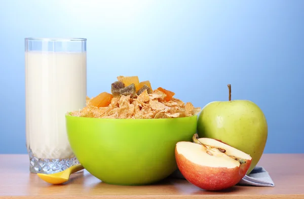 在绿色碗、 苹果和一杯牛奶上的木桌上的美味玉米片 — 图库照片