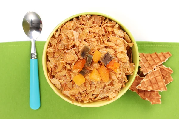 Tasty cornflakes in bowl with dried fruits on green napkin — Stock Photo, Image