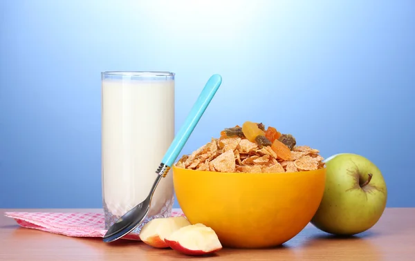 Смачні кукурудзяні пластівці в жовтій мисці, яблука і склянка молока на дерев'яному столі — стокове фото