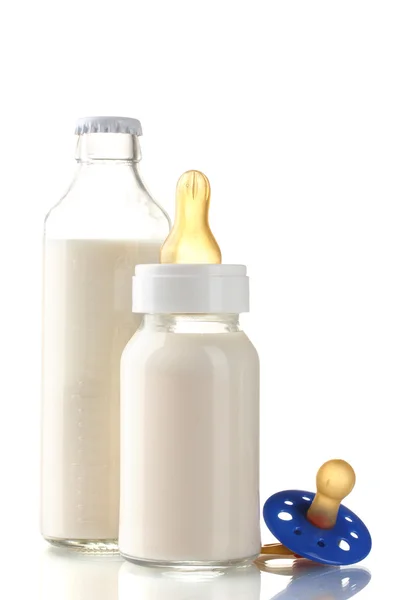 Bottles of milk and soother isolated on white — Stock Photo, Image