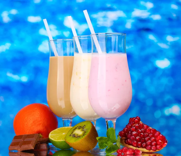 Milk shakes with fruits and chocolate on blue background — Stock Photo, Image
