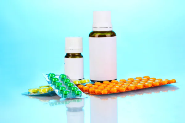 Medische flessen en tabletten op blauwe achtergrond — Stockfoto