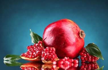 Ripe pomegranate fruit with leaves on blue background clipart