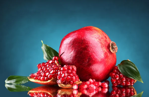 Rijp granaatappel fruit met verlaat op blauwe achtergrond — Stockfoto
