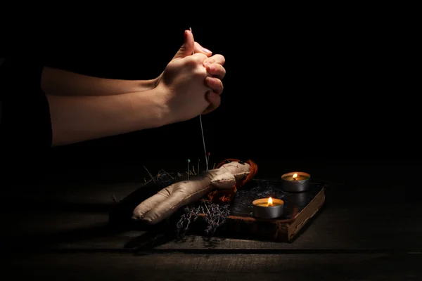 Voodoo-Puppenmädchen durchbohrt von einer Nadel auf einem Holztisch im Kerzenschein — Stockfoto