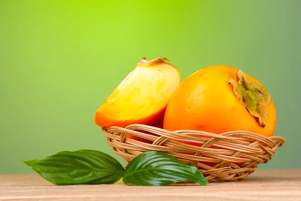 Aptitretande sharonfrukt med blad i pad på träbord på gröna bak — Stockfoto
