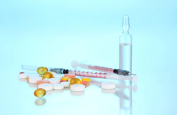 Insulinspritzen mit medizinischen Ampullen und Tabletten auf blauem Hintergrund — Stockfoto