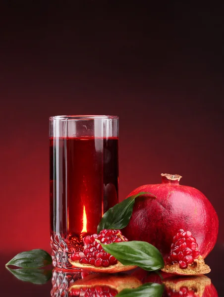 Ripe pomergranate and glass of juice on red background — Stock Photo, Image