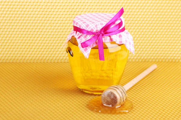 stock image Jar of honey and wooden drizzler on yellow honeycomb background