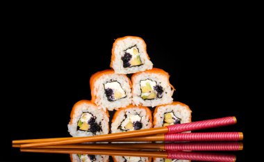 Tasty rolls with chopsticks isolated on black clipart