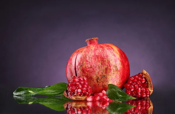 Rijp granaatappel fruit met verlaat op paarse achtergrond — Stockfoto