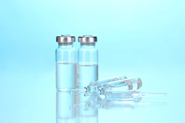 Sprutan och medicinska ampuller på blå bakgrund — Stockfoto