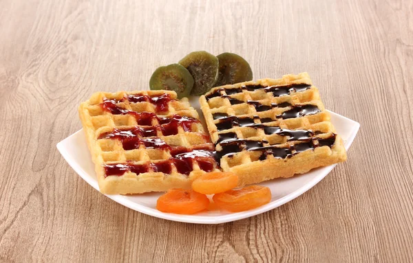Sweet waffles with jam and chocolate on plate on wooden background — Stock Photo, Image