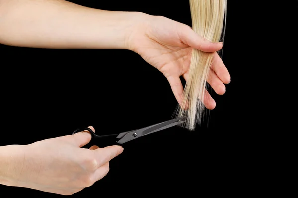 Λαμπερά μαλλιά ξανθά στα χέρια του κομμωτή που απομονώνονται σε μαύρο — Φωτογραφία Αρχείου