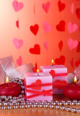 Candles for Valentine's Day on wooden table on red background clipart