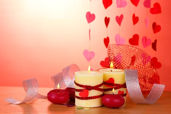 Kerzen zum Valentinstag auf Holztisch auf rotem Hintergrund — Stockfoto