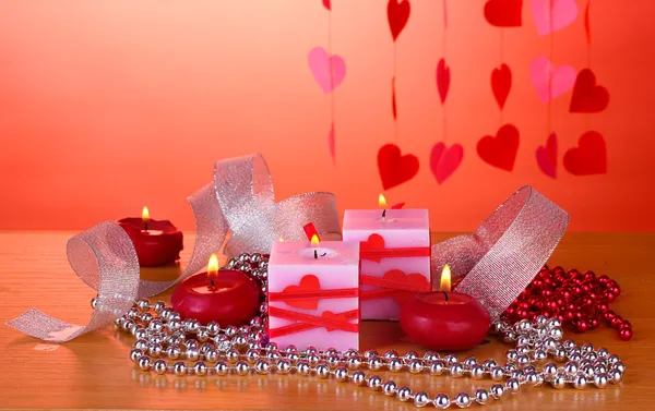 Velas para el Día de San Valentín sobre mesa de madera sobre fondo rojo —  Fotos de Stock