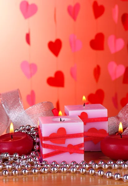 Kaarsen voor Valentijnsdag op houten tafel op rode achtergrond — Stockfoto
