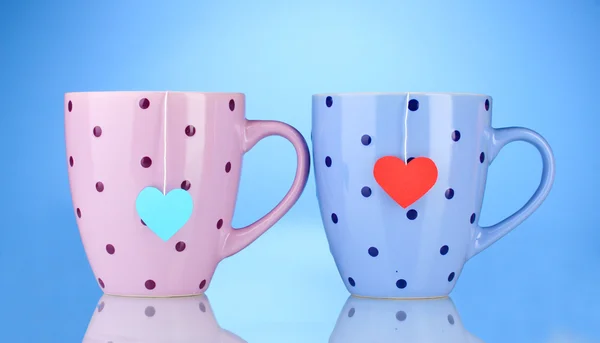 Zwei Tassen und Teebeutel mit rotem und blauem herzförmigen Etikett auf blauem Hintergrund — Stockfoto