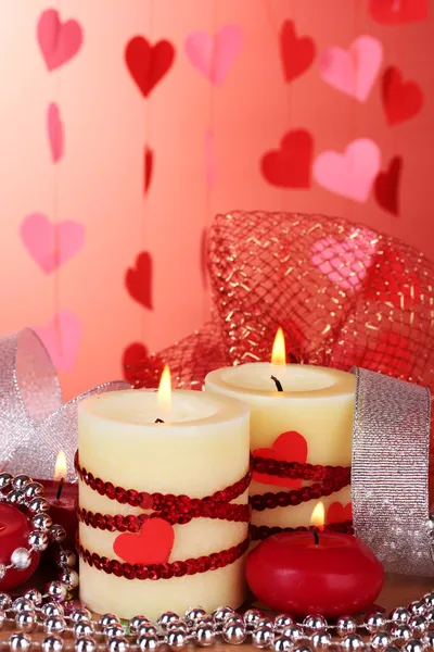 Kaarsen voor Valentijnsdag op houten tafel op rode achtergrond — Stockfoto