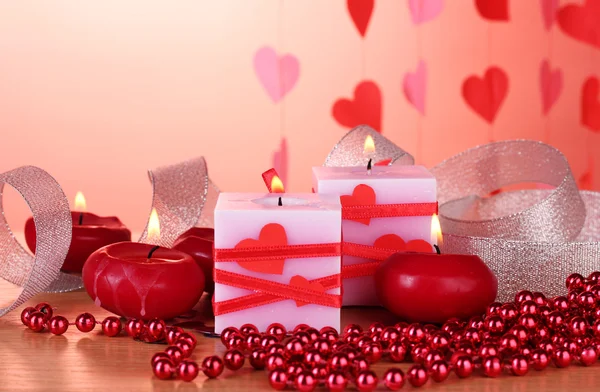 Svíčky pro den svatého Valentýna na dřevěný stůl na červeném pozadí — Stock fotografie