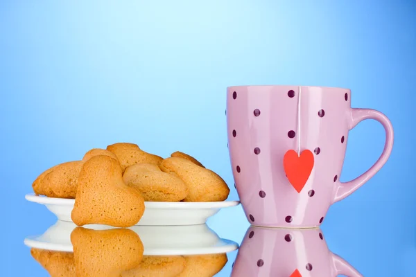 Ciasteczka w kształcie serca na płytkę i Puchar z torebkę na niebieskim tle — Zdjęcie stockowe