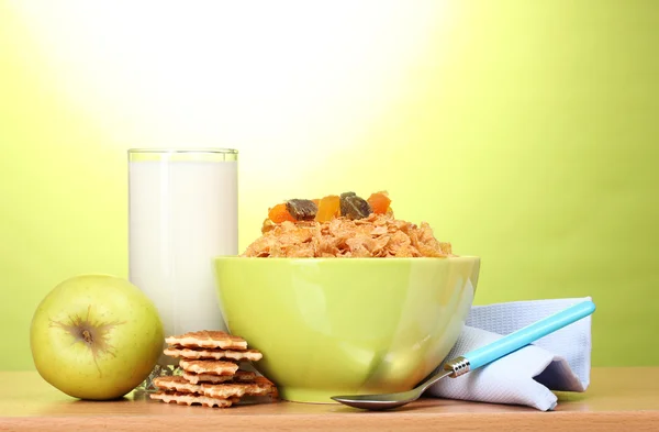 Tasty cornflakes in green bowl, apple and glass of milk on wooden table on — Stock Photo, Image