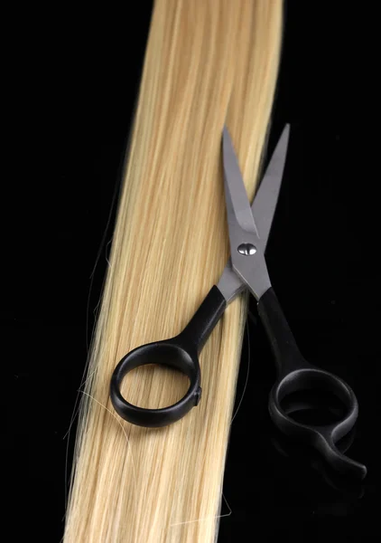 Cabello rubio brillante y tijeras de corte de pelo aisladas en negro — Foto de Stock