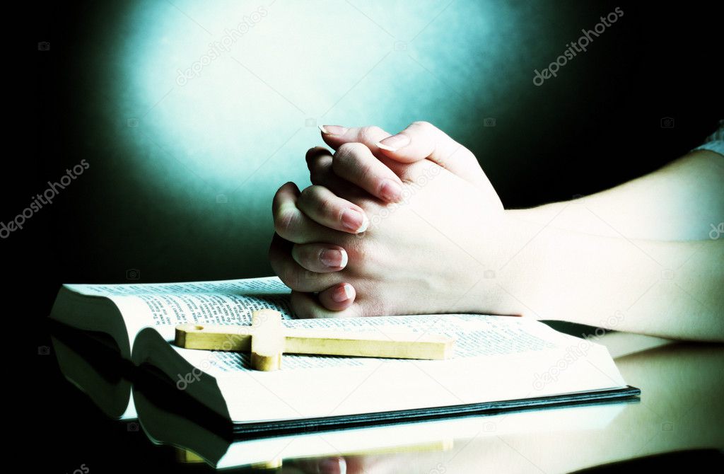 Female hands on open russian holy bible on black backround