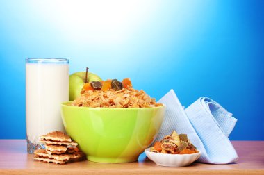 Tasty cornflakes in green bowl, apples and glass of milk on wooden table on clipart