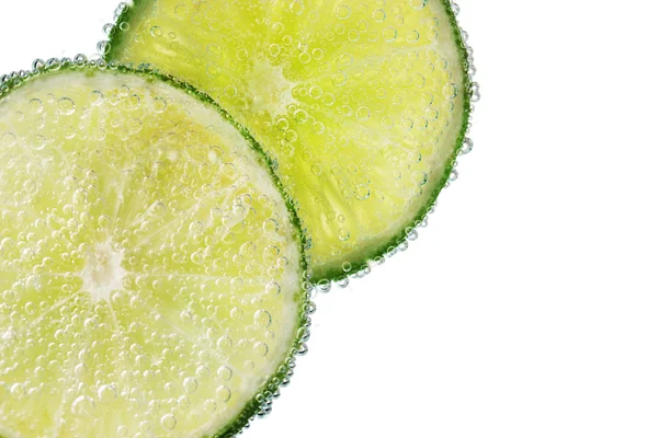Slices of lime in the water with bubbles — Stock Photo, Image