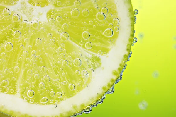 Zitronenscheibe im Wasser mit Blasen — Stockfoto