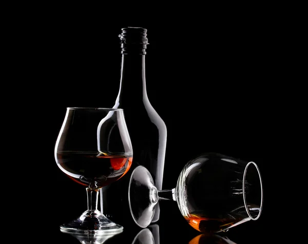 काळ्या पार्श्वभूमीवर ब्रँडी आणि बाटलीचे चष्मा — स्टॉक फोटो, इमेज