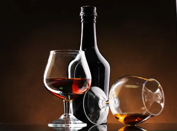 Gläser Schnaps und Flasche auf braunem Hintergrund — Stockfoto
