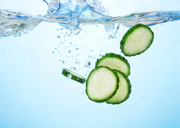 stock image Fresh sliced cucumber in water on blue background