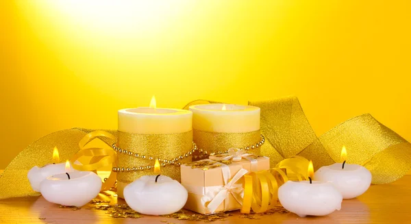 Красиві свічки, подарунки та декор на дерев'яному столі на жовтому тлі — стокове фото