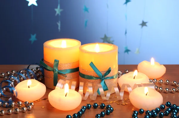 Belas velas, presentes e decoração em mesa de madeira no fundo azul — Fotografia de Stock