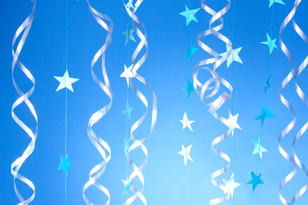 Hermosas serpentinas y estrellas sobre fondo azul —  Fotos de Stock