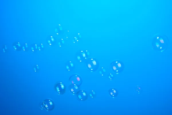 青の背景に泡立つ石鹸 — ストック写真