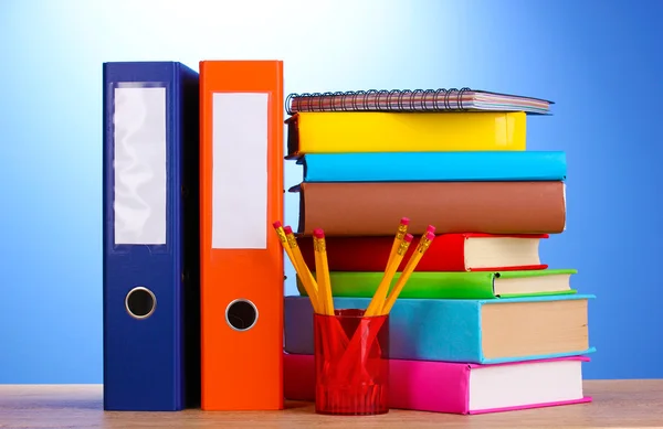 Jasne biuro folderów i książek z papeterii na drewnianym stole na niebieski bac — Zdjęcie stockowe