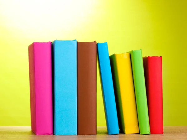 Boeken verblijf op houten tafel op groene achtergrond — Stockfoto
