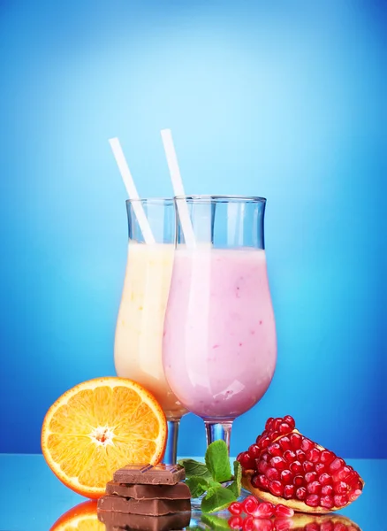 Milchshakes mit Früchten und Schokolade auf blauem Hintergrund — Stockfoto