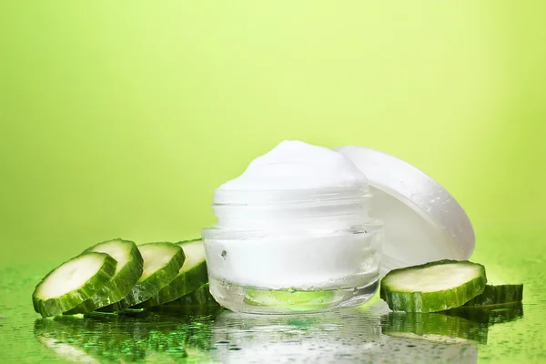 Crema y pepino fresco en rodajas sobre fondo verde — Foto de Stock