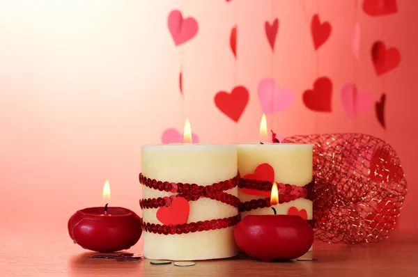 Kerzen zum Valentinstag auf Holztisch auf rotem Hintergrund — Stockfoto