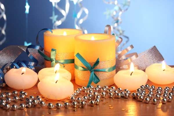 Beautiful candles, gifts and decor on wooden table on blue background Stock Picture