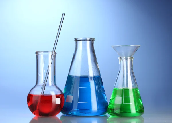 同颜色的液体与反射在蓝色背景上的三个烧瓶 — 图库照片